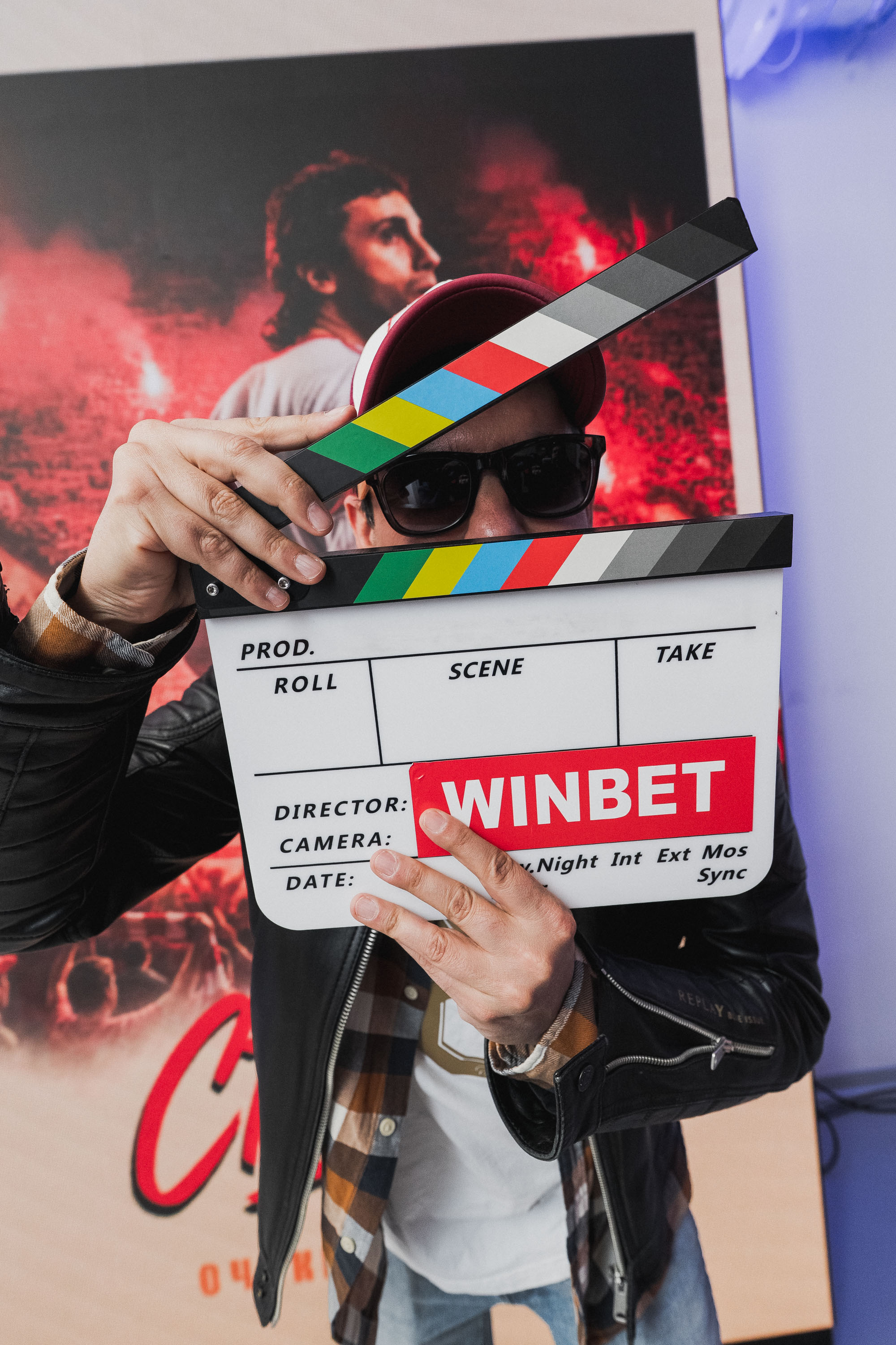 режисьорът Мартин Макариев държи филмова клапа с логото на WINBET пред плакат на Христо Стоичков по време на събитието