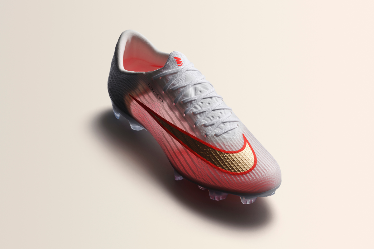 Продуктова снимка на мъжка футболна обувка Nike Mercurial Flyweave Ultra в бяло с преливащ червен нюанс, златиста запетая на Nike и прозрачна подметка със шипове.