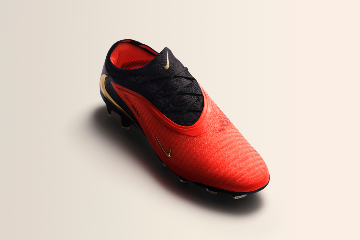 Продуктова снимка отгоре под ъгъл на мъжка футболна обувка Nike Phantom в яркочервен цвят с черна горна част при връзките и златисто лого Swoosh.
