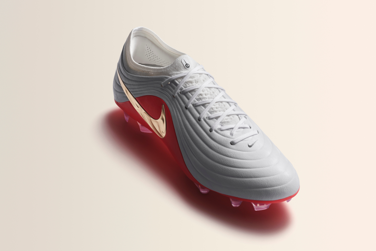 Продуктова снимка под ъгъл на мъжка футболна обувка Nike Tiempo Legend в светлосив цвят с релефна кожена горна част, червена подметка и огледално златиста запетая отстрани.
