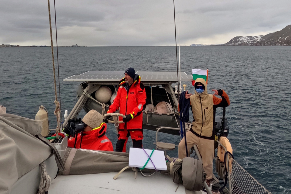 Екипажът на Mirabo Adventures на борда на ветроходна лодка в открито море, облечен в професионална екипировка Helly Hansen от SPORT DEPOT и българското знаме на заден план.