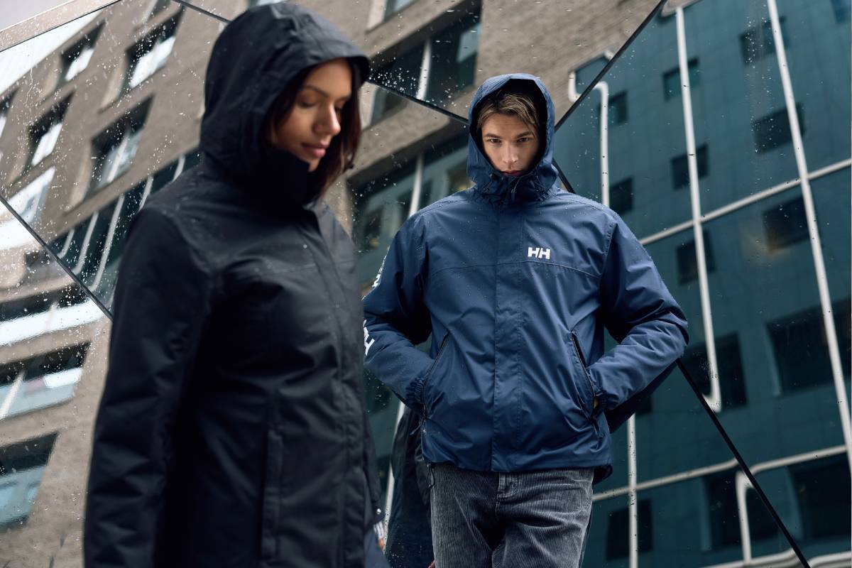 Мъж и жена с непромокаеми якета Helly Hansen на градски фон
