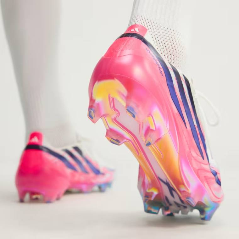 Близък план на бели футболни обувки adidas F50 Hyperfast Elite FG с бутони за терен със суха естествена трева 