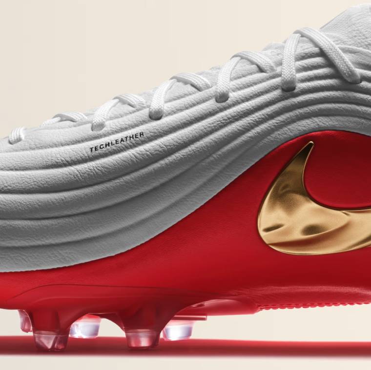 Страничен поглед към бяла футболна обувка Nike Tiempo Maestro Elite FG със златисто лого и червен детайл.
